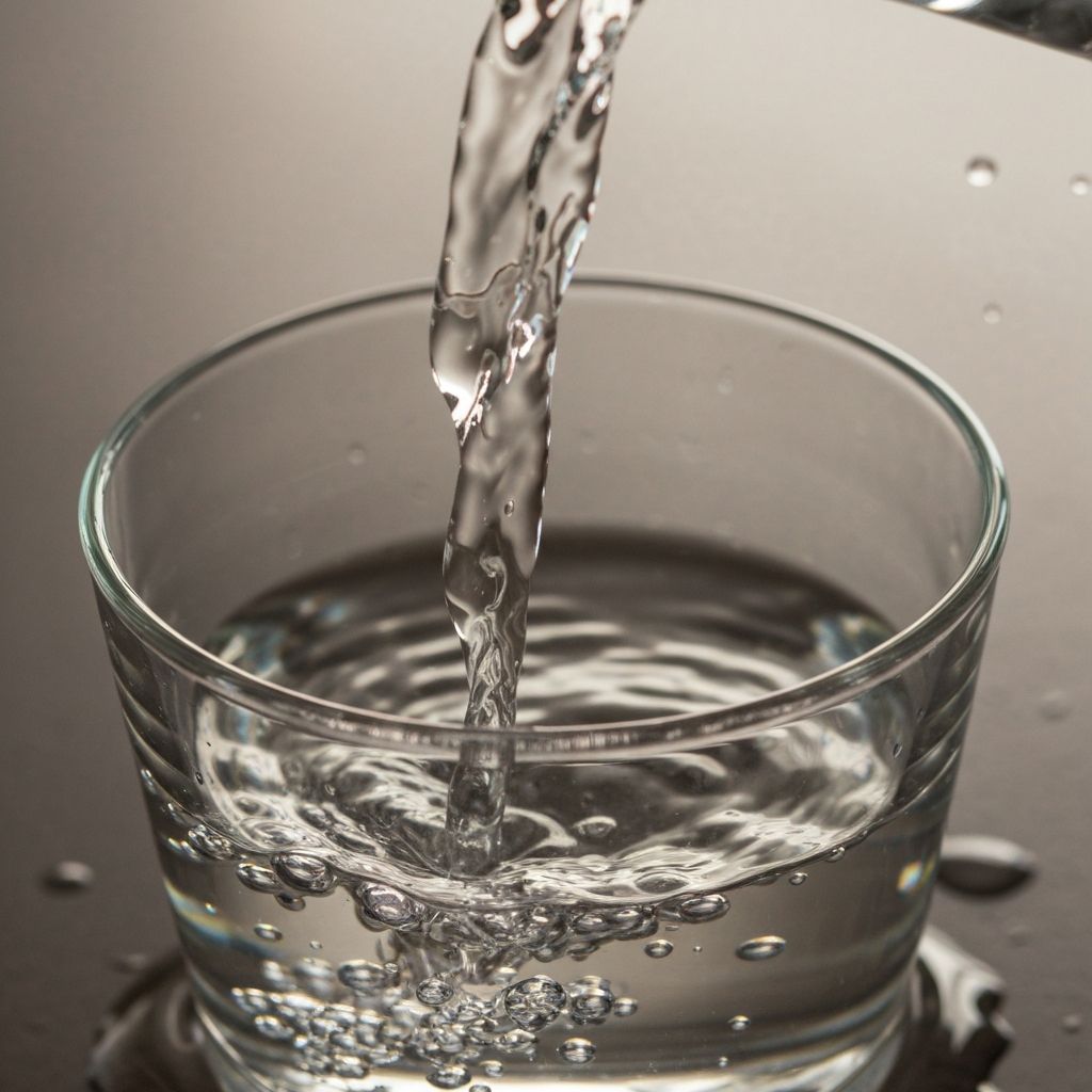 Crystal clear water pouring into glass cup with natural lighting and clean composition